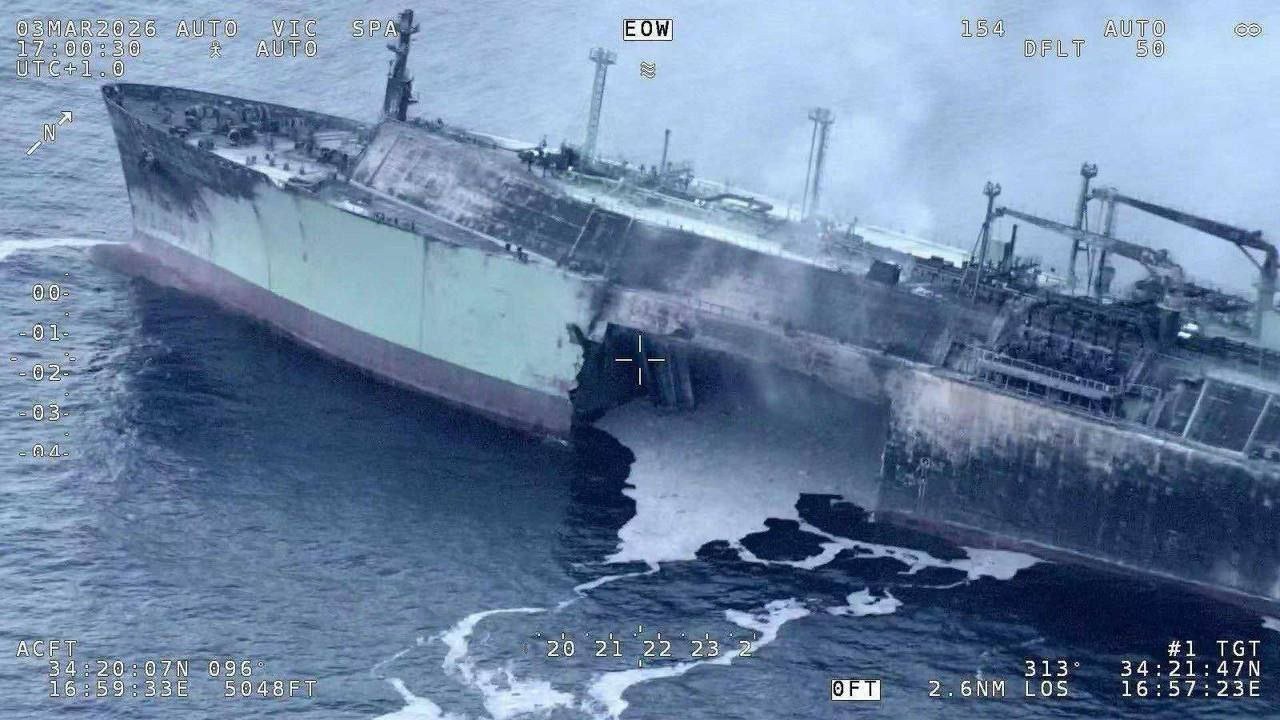 Closer aerial, 3 March 2026: opening in the starboard side, smoke still rising. Frame shows damage, not a perpetrator.