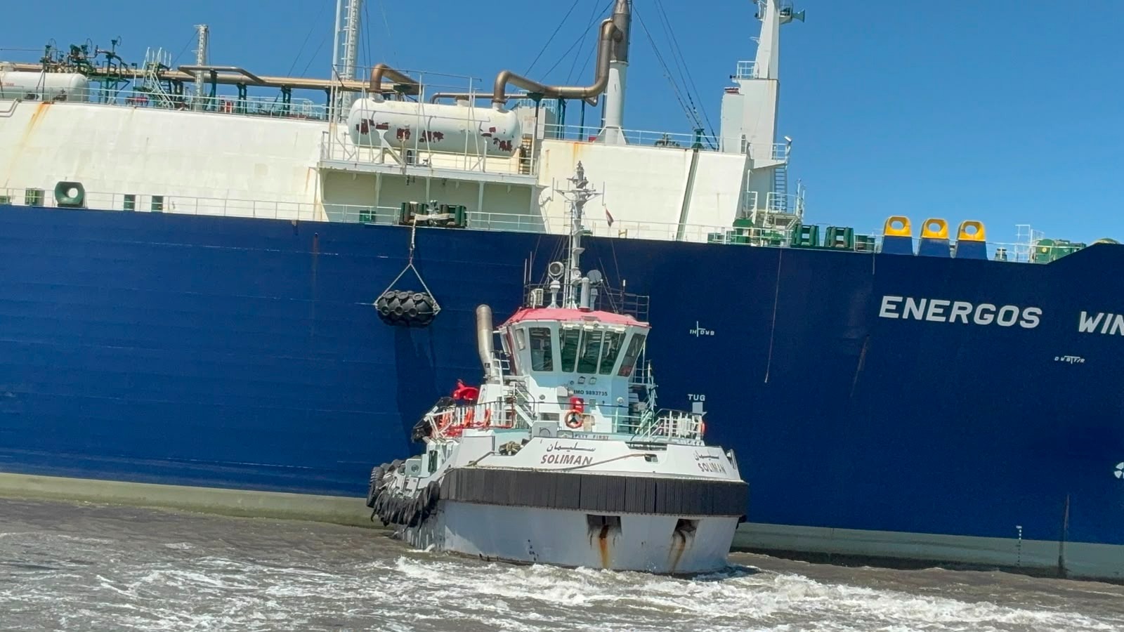 Tug Soliman (سليمان) on the starboard side of Energos Winter. Names visible on both hulls. Assist / refloat. Not the 29 July fire.