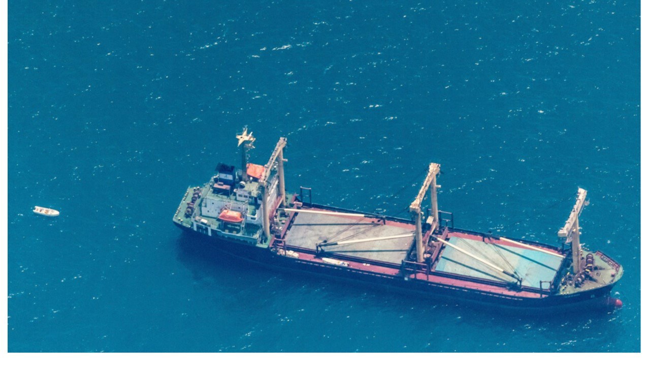 Aerial. General cargo, SWARD on the port bow, three deck cranes, small white skiff off port aft.