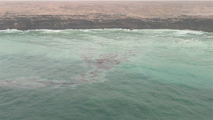 Oil in the water off a cliffed coast.